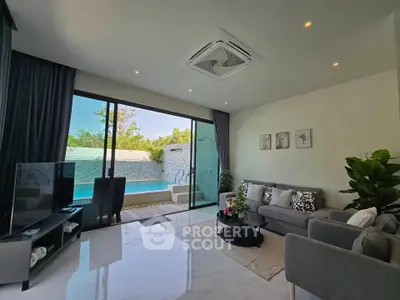 Luxurious living room with pool view, modern decor, and ample natural light.