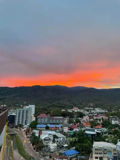 Stunning sunset view over a vibrant cityscape with lush hills in the background.