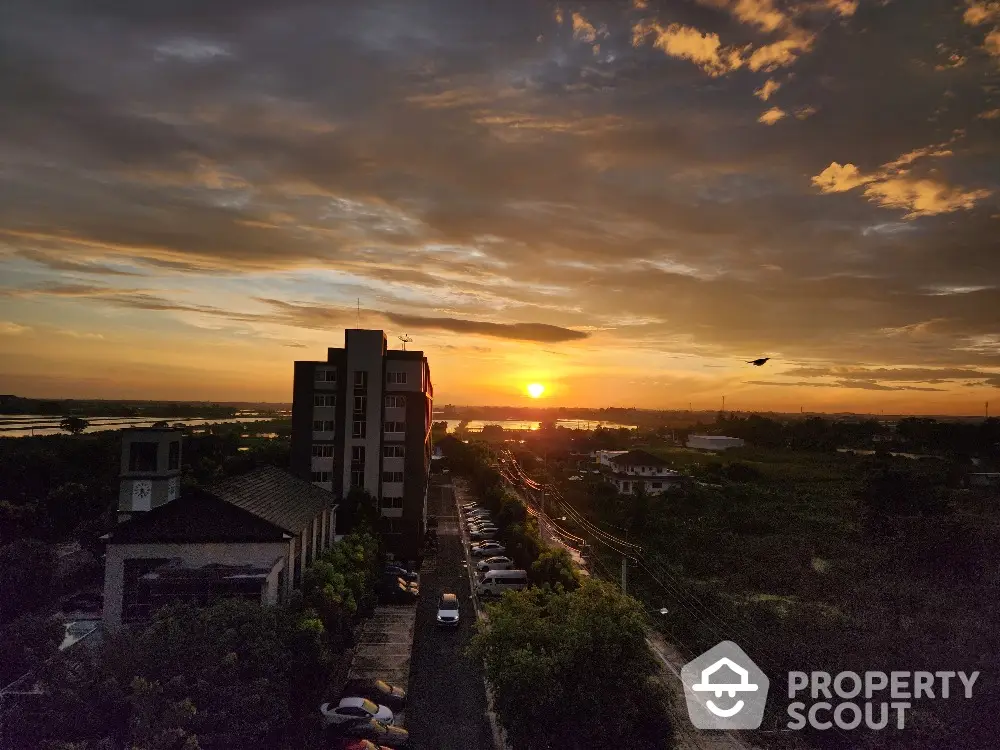 Stunning sunset view from high-rise building overlooking serene landscape and river.