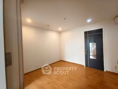 Spacious empty room with wooden flooring and modern door
