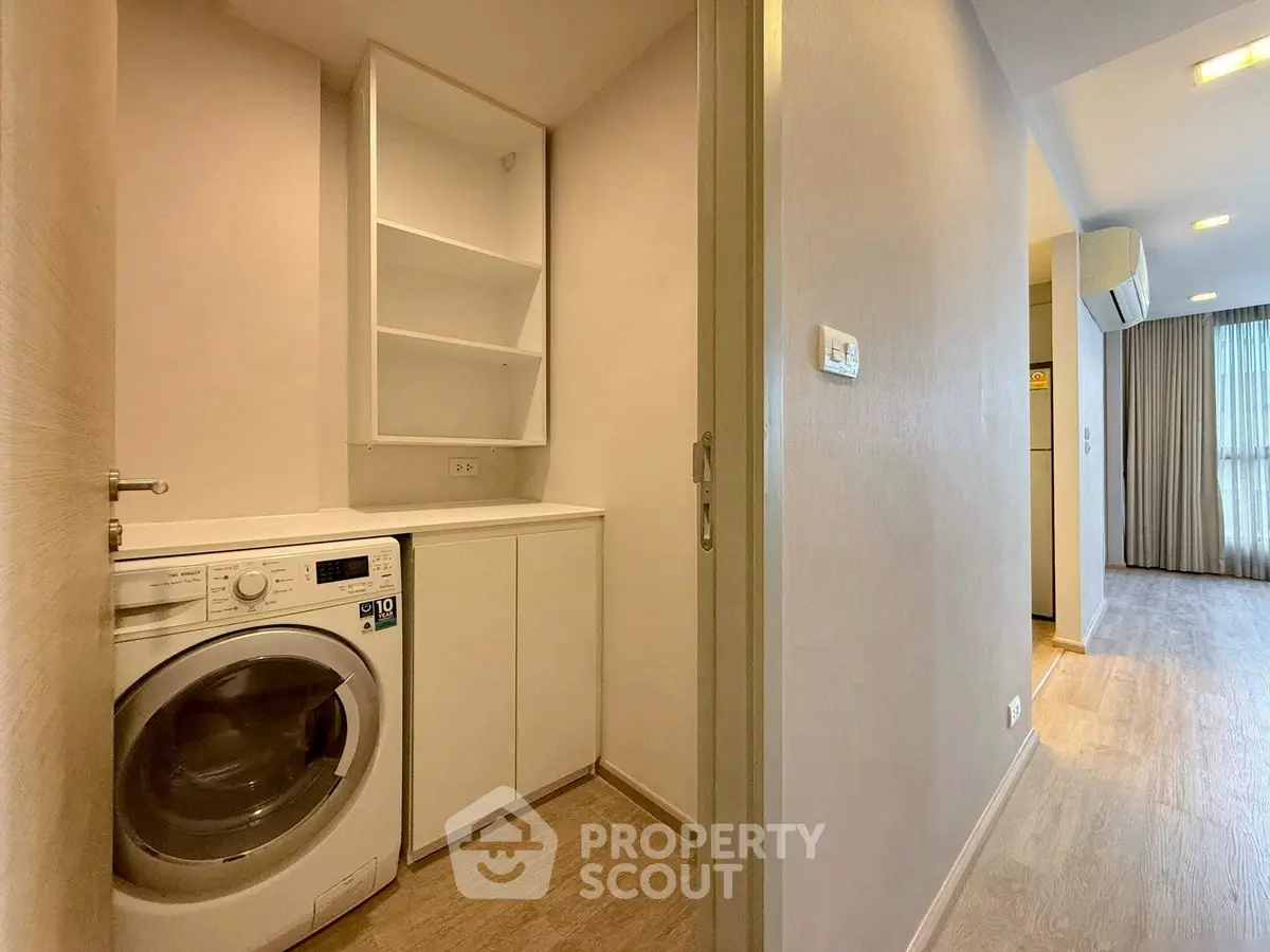 Modern apartment hallway with built-in washing machine and storage shelves.