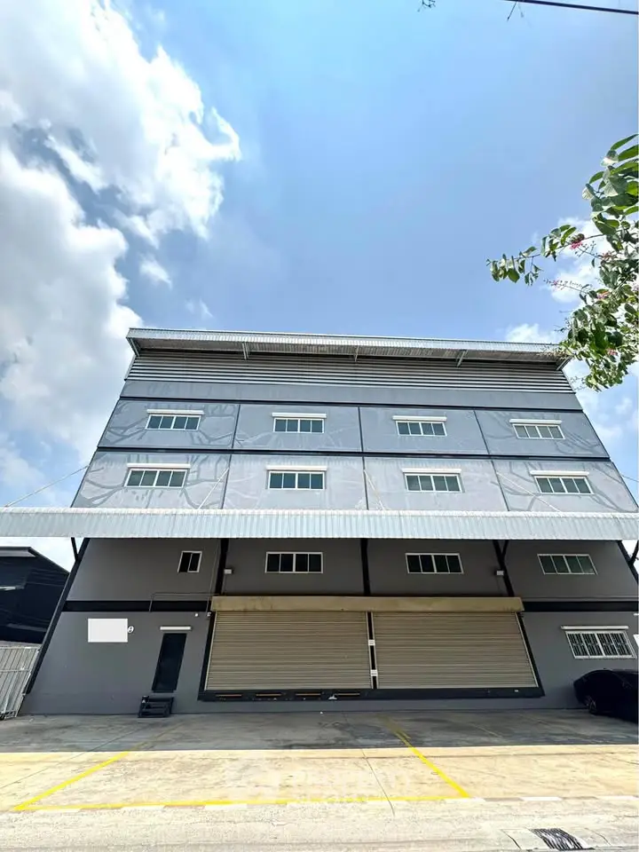 Modern industrial building with sleek design and spacious parking area under a clear blue sky.