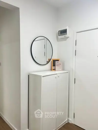 Modern entryway with sleek white cabinet and round mirror