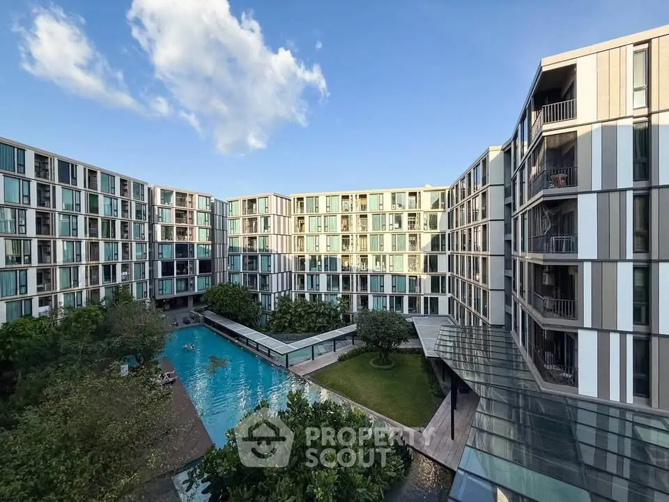 Modern apartment complex with pool and garden view, showcasing contemporary architecture and lush greenery.