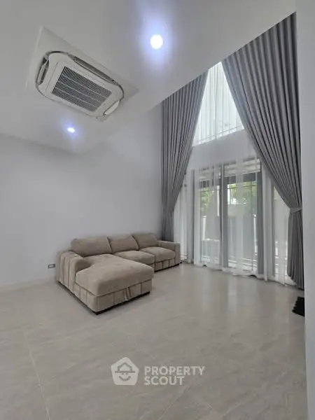 Spacious modern living room with high ceilings and elegant curtains