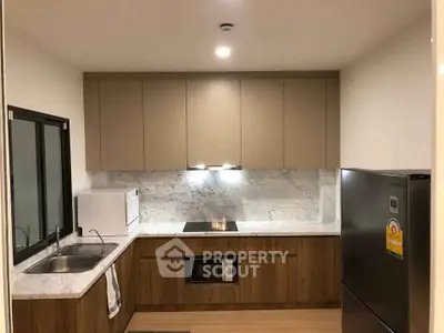 Modern kitchen with sleek cabinetry, marble backsplash, and stainless steel appliances.