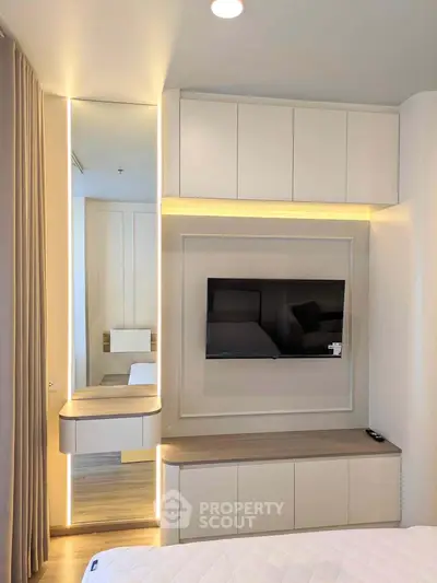 Modern bedroom with sleek built-in storage and wall-mounted TV