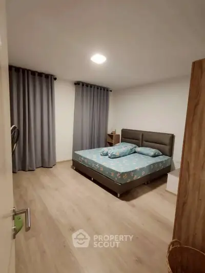 Spacious bedroom with modern decor and cozy ambiance, featuring elegant curtains and stylish flooring.