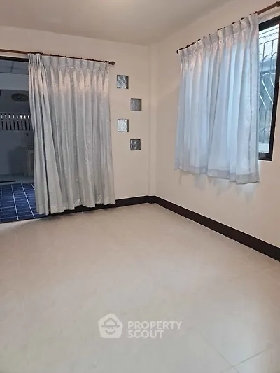 Spacious empty room with tiled floor and large windows, ideal for customization.