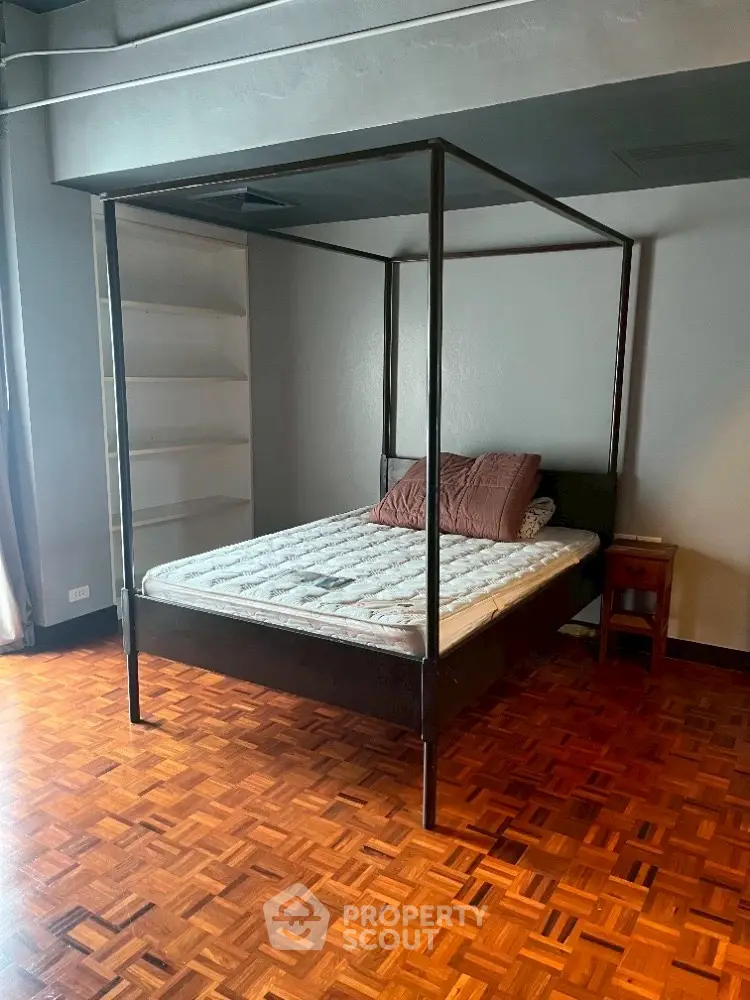 Spacious bedroom with elegant four-poster bed and parquet flooring.
