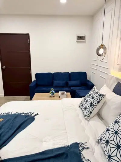 Cozy bedroom with stylish blue sofa and modern lighting, perfect for relaxation and comfort.