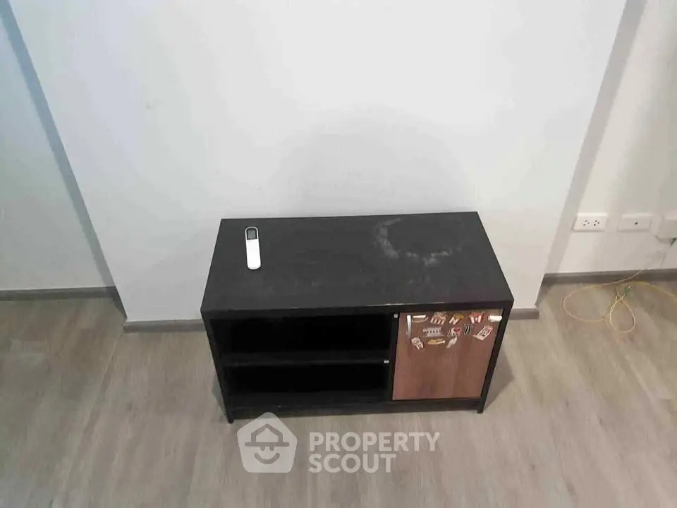 Minimalist living room with modern TV stand and remote control on wooden floor.
