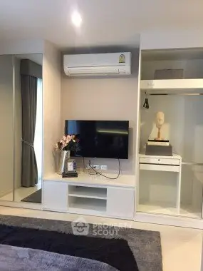 Modern bedroom with sleek TV setup and air conditioning in stylish apartment.
