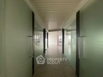 Modern hallway with glass doors leading to a bright open space