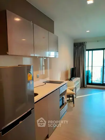 Modern kitchen with sleek cabinets and appliances in a bright apartment with balcony view.
