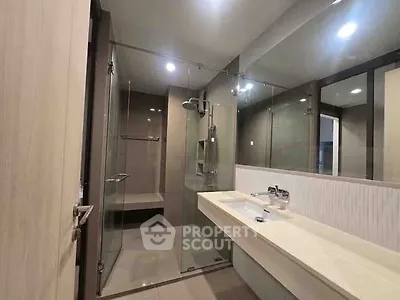 Modern bathroom with glass shower and sleek vanity in contemporary apartment.