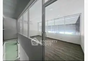 Spacious modern office space with glass partitions and wooden flooring.