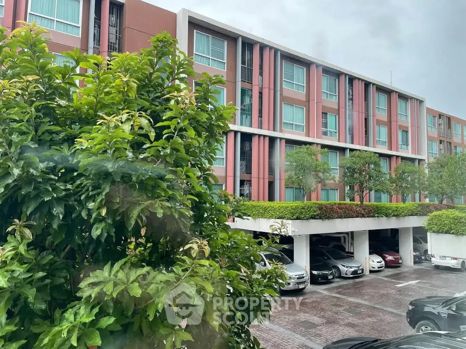 Modern apartment building with lush greenery and parking area, ideal for urban living.