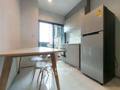 Modern kitchen with sleek design, featuring a dining table and stainless steel fridge.