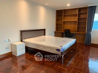 Spacious bedroom with wooden flooring and built-in shelves, perfect for a cozy and organized living space.