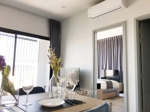 Modern open-plan living and dining area with bedroom view, featuring stylish decor and natural light.