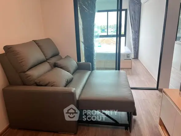 Modern living room with stylish sofa bed and large window view in a contemporary apartment.