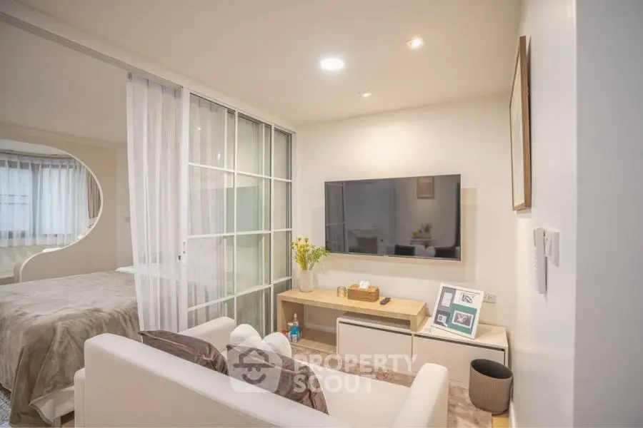Modern living room with sleek TV setup and cozy bedroom view