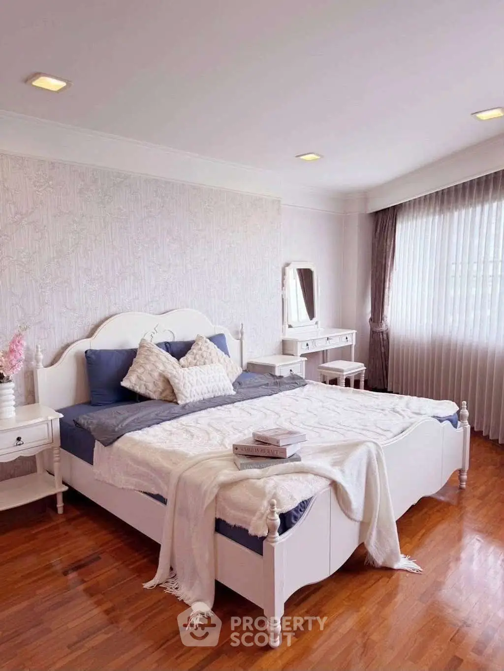 Elegant bedroom with stylish decor and natural light, featuring a cozy bed and wooden flooring.