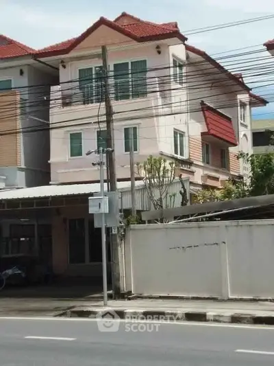 Charming three-story townhouse with red roof and modern facade, ideal for urban living.