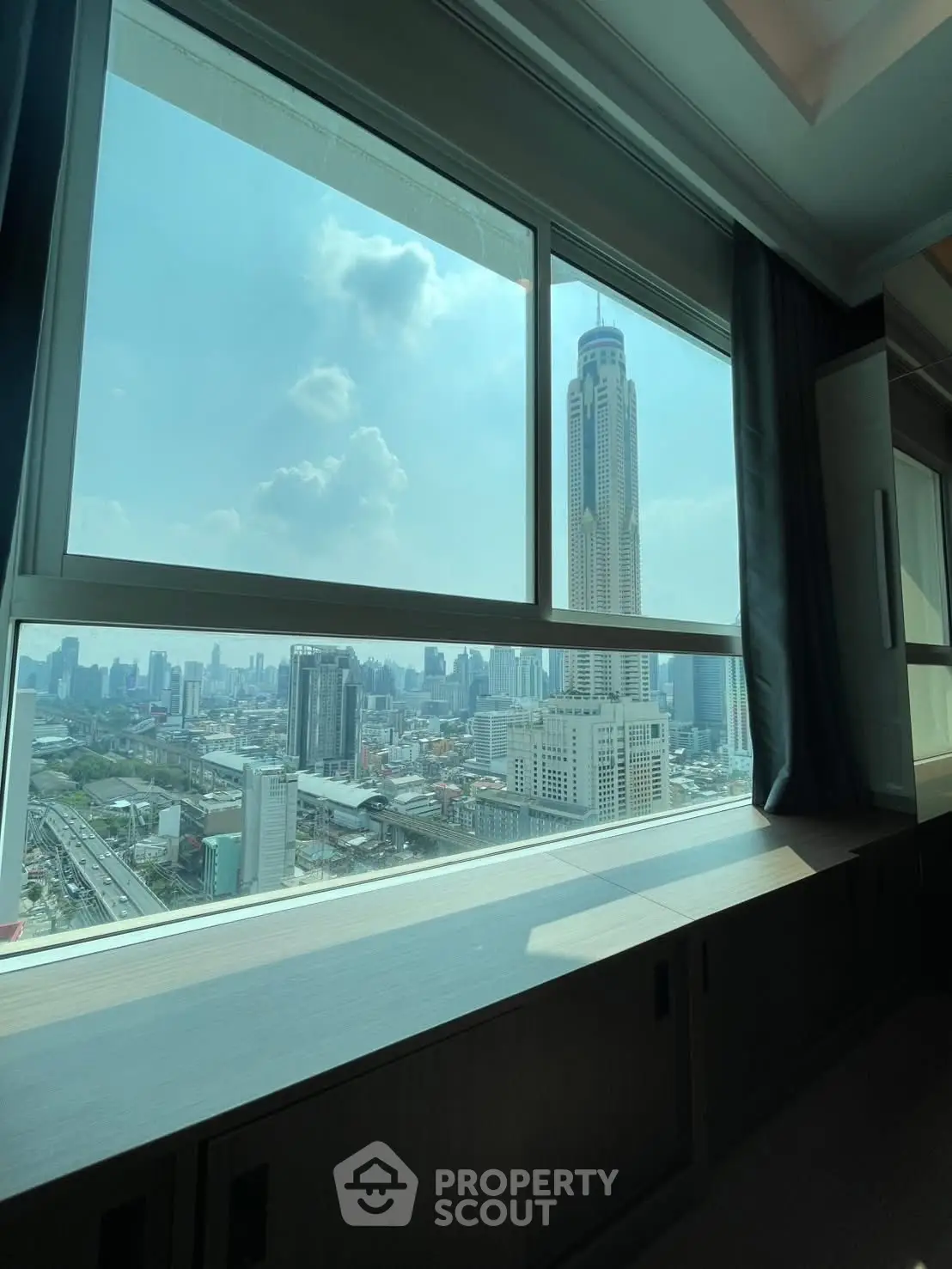 Stunning cityscape view from high-rise apartment window, showcasing urban skyline and iconic tower.