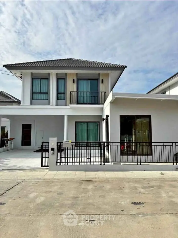 Modern two-story house with sleek design and spacious driveway in suburban neighborhood.