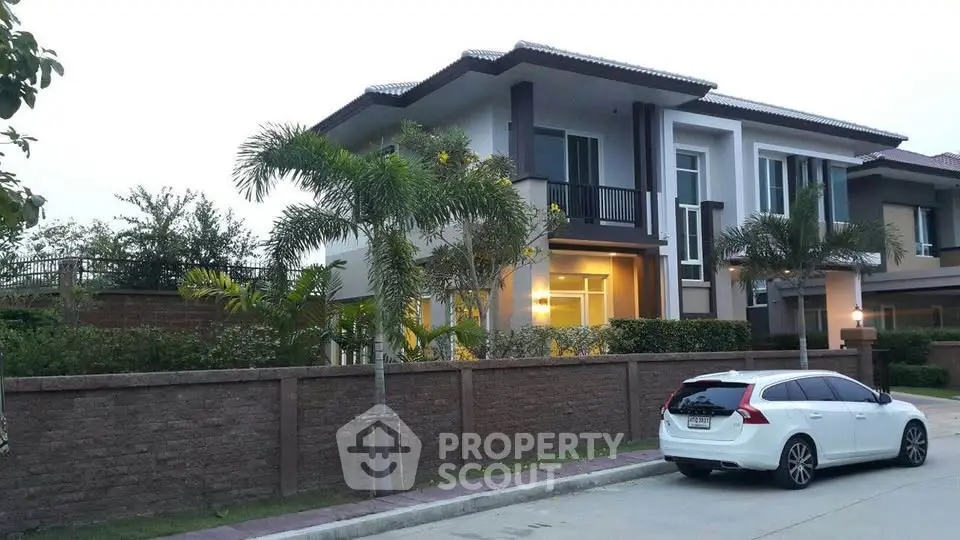 Modern two-story house with a sleek design and lush landscaping, featuring a spacious driveway and elegant facade.
