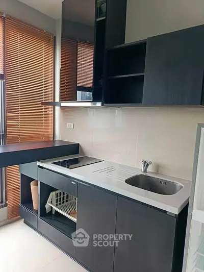 Modern kitchen with sleek black cabinetry and integrated appliances in a stylish apartment.