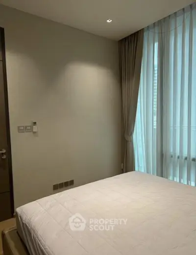 Modern bedroom with large window and elegant curtains in a stylish apartment.