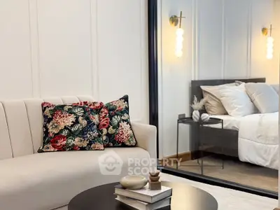 Elegant living room with floral cushions and view into a cozy bedroom, showcasing modern interior design.
