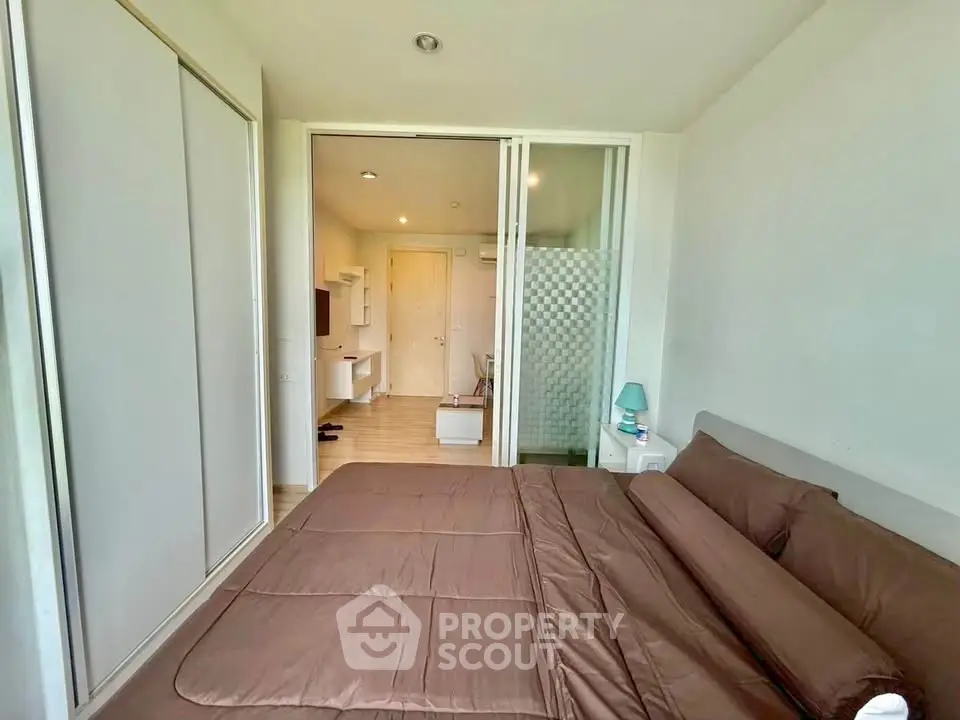 Modern bedroom with sliding closet doors and cozy brown bedding in a stylish apartment.