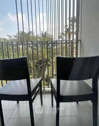 Charming balcony with two chairs offering a serene view of lush greenery, perfect for relaxation.