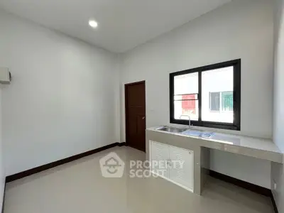 Spacious minimalist kitchen with sleek countertops and ample natural light.