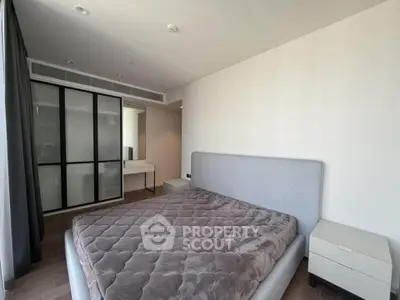 Modern bedroom with sleek design and ample natural light, featuring a stylish bed and built-in wardrobe.
