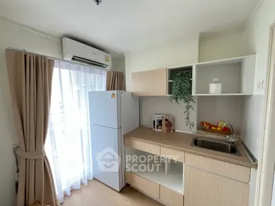 Modern kitchen with sleek cabinetry and natural light, featuring a fridge and air conditioning unit.