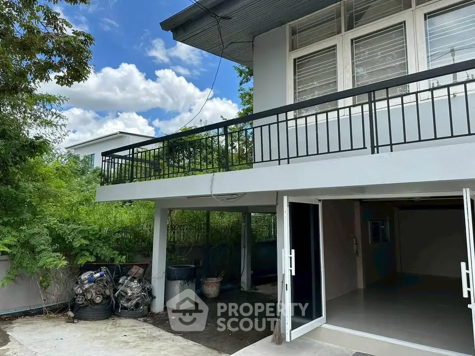 Spacious property with open garage and balcony, surrounded by lush greenery, perfect for family living.