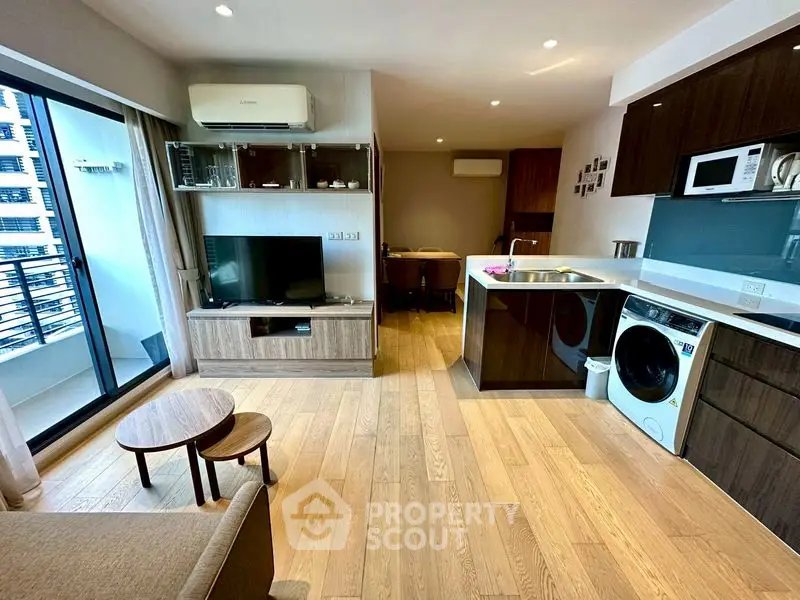 Modern open-layout living room with balcony, featuring wooden flooring and stylish furniture.