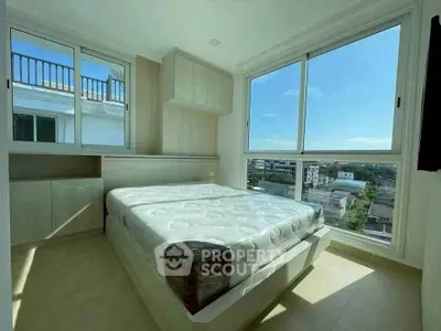 Bright bedroom with large windows offering stunning city views and ample natural light.