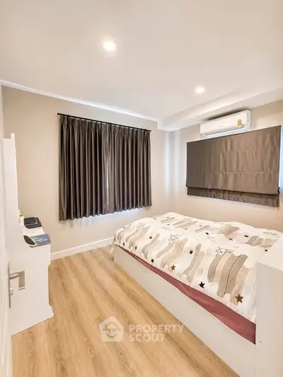 Modern bedroom with wooden flooring and stylish decor in a cozy apartment.