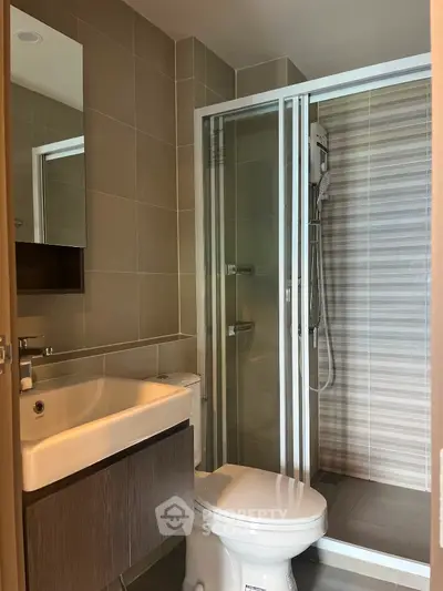 Modern bathroom with glass shower and sleek fixtures in contemporary apartment.