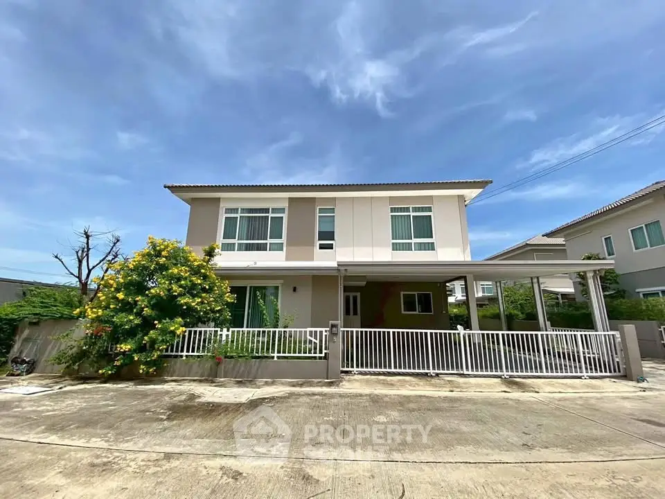Modern two-story house with a spacious driveway and lush greenery under a clear blue sky.
