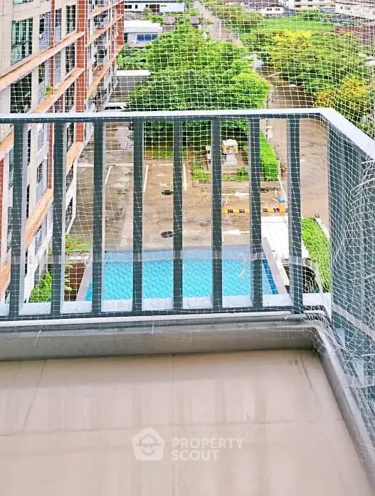 Modern balcony with safety net overlooking pool and lush greenery in urban setting.