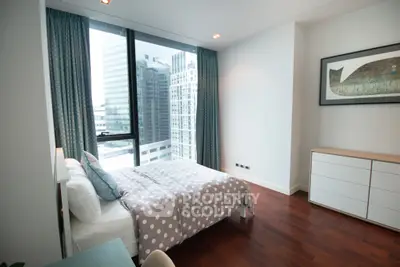 Modern bedroom with city view and stylish decor in high-rise apartment.