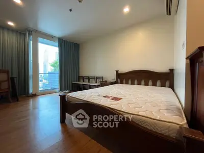 Spacious bedroom with wooden flooring and balcony view in modern apartment