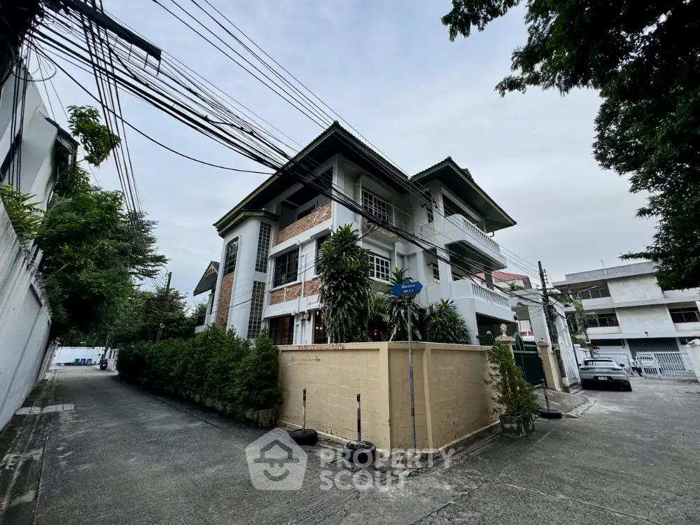 Charming corner unit building with lush greenery and spacious balconies in a serene neighborhood.